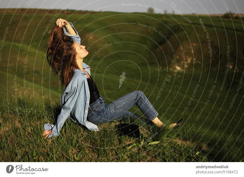 Young woman is sitting on green grass hills and feeling relax on summer sunny day mountain young agriculture people plant road savannah scenery scenic sky
