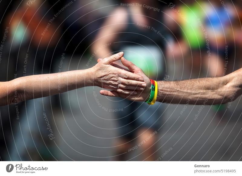 The solidarity handshake in sport. Support during the physical effort of the race of an athlete running the marathon. arms background cheering closeup concept