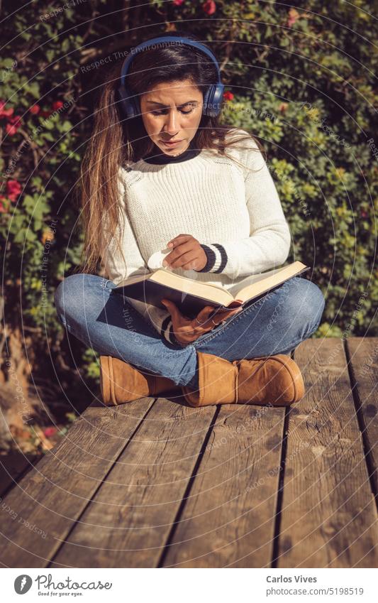 latina woman, sitting outdoors listening to music and reading 40s 50s Latin woman alone beautiful bestseller comfort comfortable concepts copy space cozy