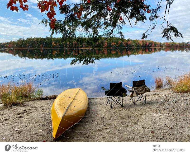 Fall scene at Kejimkujik National Park.  Bright yellow canoe and camp chairs on the beach. lake Autumn leaves vacation relaxation nature landscape