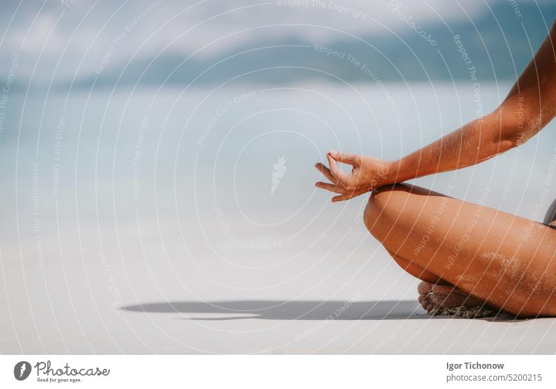 Rear view of a woman hands and legs in meditating pose on sandy beach. Tropical recreation vacation bikini sea rear turquoise seychelles sky summer nature