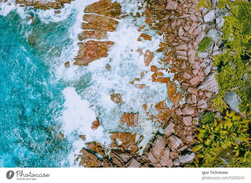 Aerial drone photo of Seychelles tropical beach Anse Cocos at La Digue Island. White rolling waves splash granite coastal rocks. Travel and vacation concept