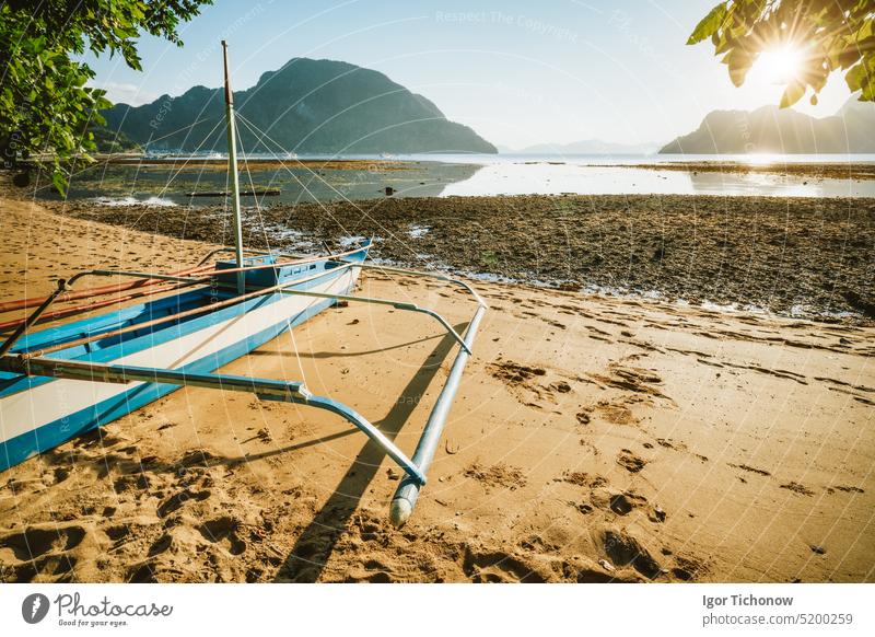 Bangka boat on sandy beach with golden sunset light over tropical islands in background. El Nido bay. Philippines philippines beautiful silhouette nature travel