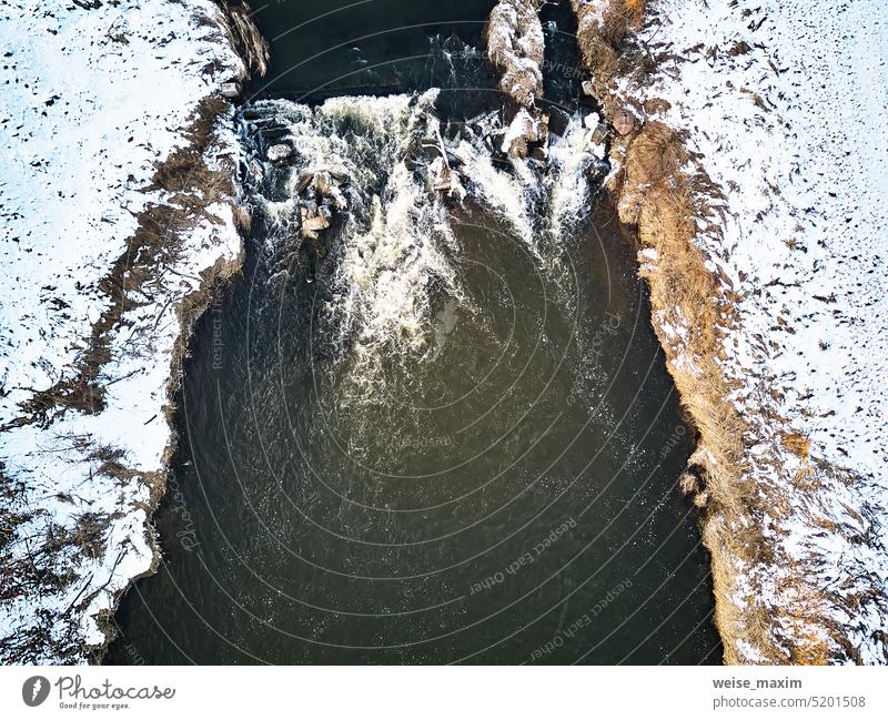 Waterfall on winter creek. Snow on frozen riverbanks. Top Aerial View Of River Cascade. Stream water flowing between rocks waterfall snow cascade aerial stream