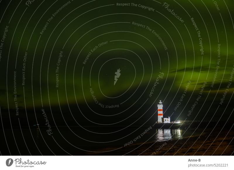 small lighthouse on the North Atlantic at night, illuminated and with a beautiful northern lights in the sky. Lighthouse Beacon Safety Old Atlantic Ocean