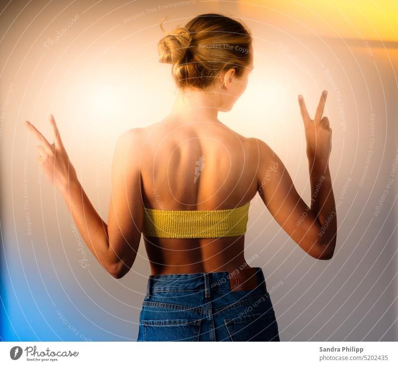 Portrait of a young woman from behind makes the peace sign portrait young woman Peace Symbols and metaphors Ukraine War Solidarity Peace Wish Blue