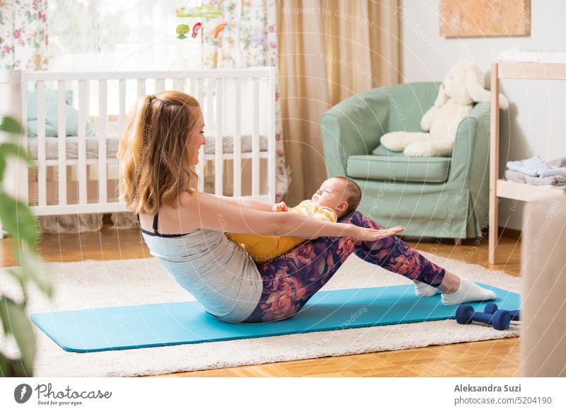 Young mother working out at home on a mat with baby. Interior of a cozy sunny nursery room. Woman practicing yoga together with child. active asana bonding