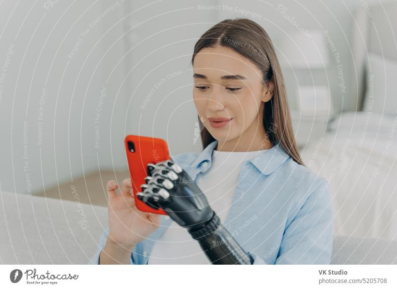 Happy disabled young girl with bionic arm prosthesis holding smartphone, shopping in online store hand e commerce artificial apps healthcare message