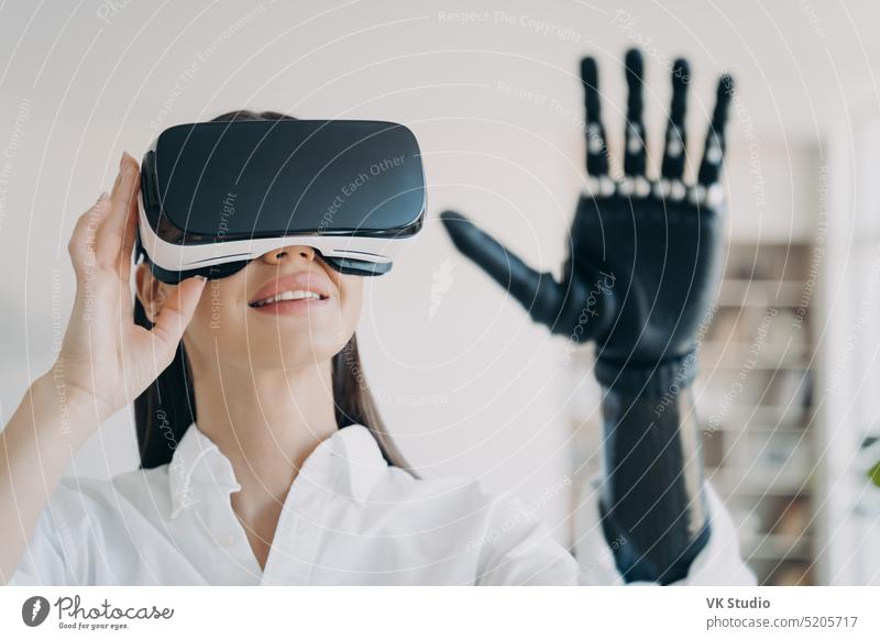 Woman with bionic prosthetic arm testing virtual reality glasses, experiencing augmented cyberspace prosthesis disabled female disability healthcare palm girl