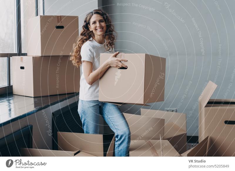 Excited girl carrying carton box with things for relocation to new home apartment. Mortgage, moving female parcel package delivery service hold renter charity