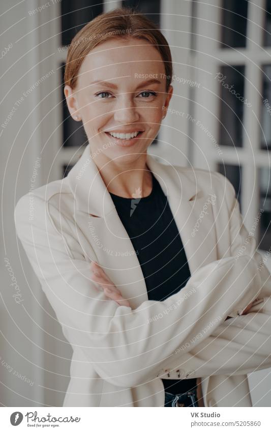 Happy businesswoman with her arms crossed. Stylish young adult european lady in white jacket. formal portrait confidence elegance expression femininity studio