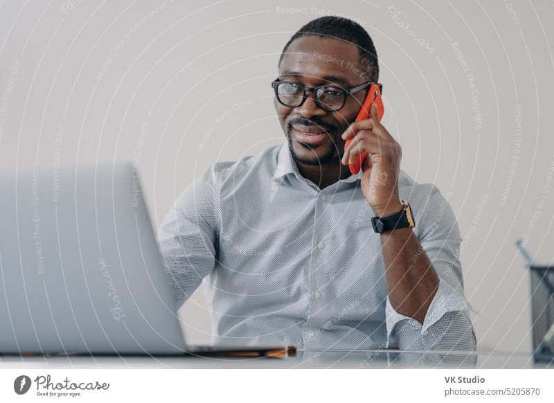 African american businessman makes business call, talking on phone, discussing working at laptop african american office manager communicate project answer