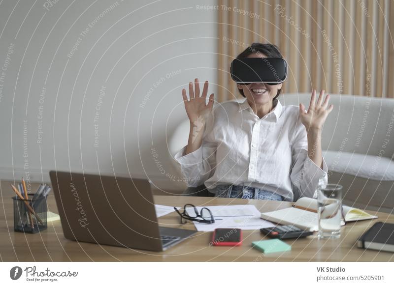 Excited businesswoman wearing virtual reality glasses while working in office excited employee vr headset goggles touch 3d play digital cyberspace enjoying