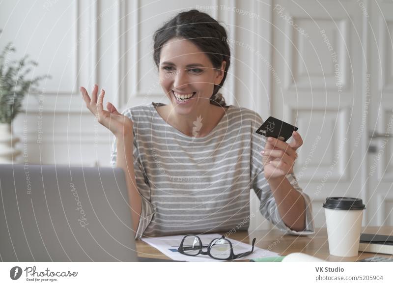 Young smiling italian woman making payment with plastic card during online shopping on laptop happy credit young spanish ecommerce shopper transfer customer