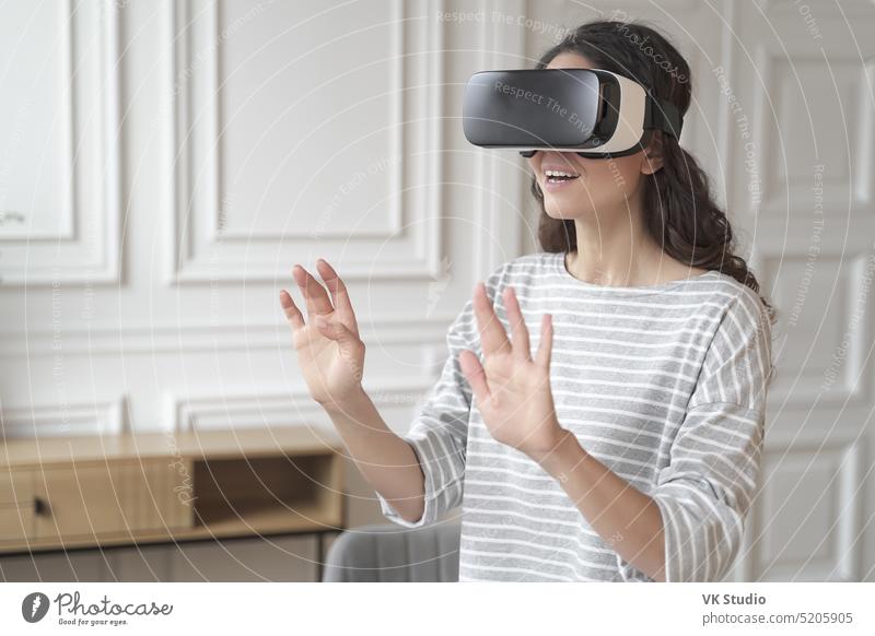 Young impressed brunette businesswoman interacting with virtual reality wearing VR headset glasses employee vr goggles touch air hand technology device game