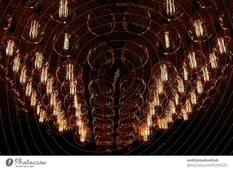 Stylish, modern and decorative lamps of Edison of round shape in the rows. Light bulbs in retro style. A lot celling glowing vintage LED lamps. Object for interior decoration, selective focus photo