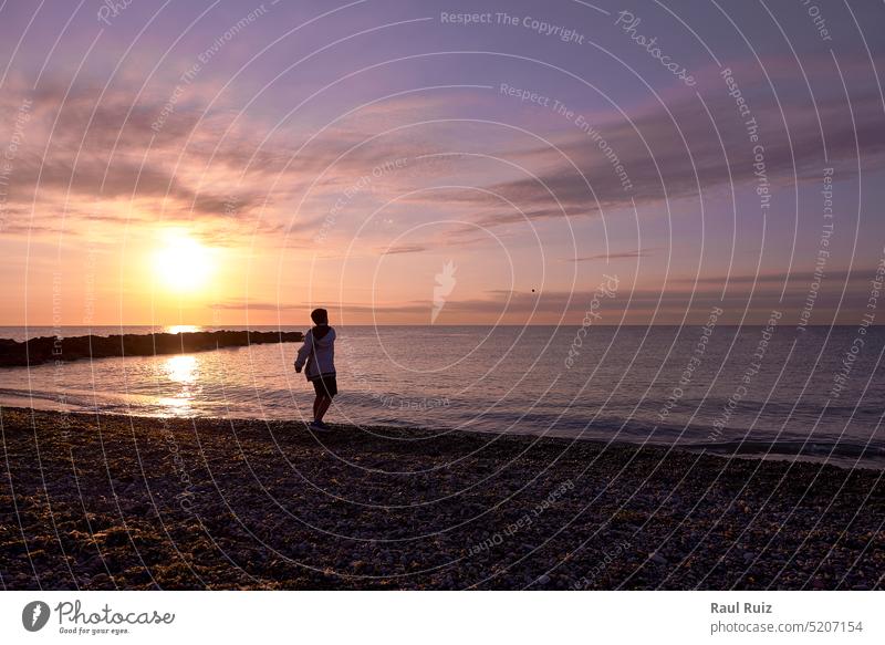 Boy playing pebble throwing on the beach at dawn dusk fantasy horizon panorama panoramic peaceful reflection scenery seascape sunrise time weather long sole