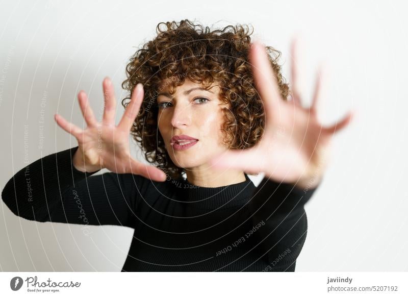 Focused woman stretching arms and showing stop gesture with full open palms sign model curly hair demonstrate warning finger style advertise appearance young