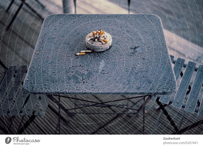 Full ashtray with cigarette butts on icy garden table Ashtray Cigarette Smoking dumb Cigarette Butt stop Table icily Garden table Cold out go out intent Good