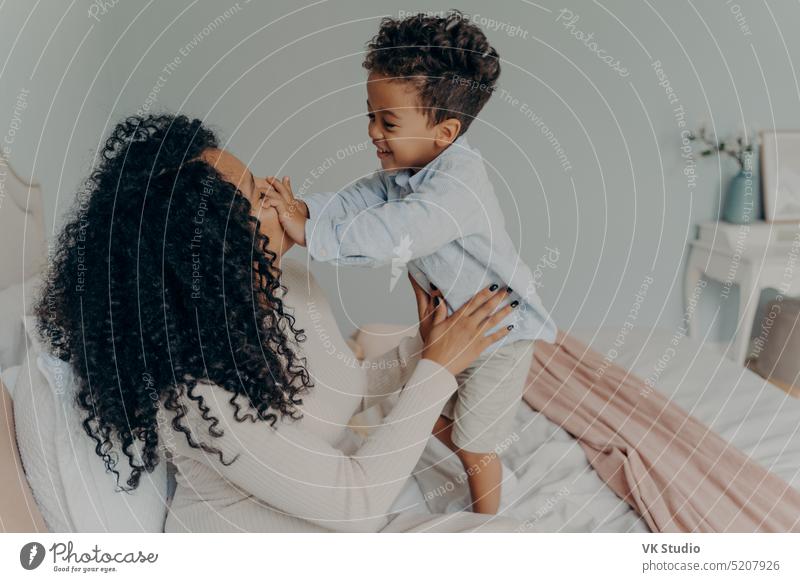 Pregnant afro american lady playing with her son at home family african pregnant mother cute boy little spending mom child hugging mised race young enjoying bed
