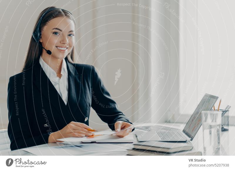 Positive young businesswoman preparing for online presentation economist report financial web conference call headset office entrepreneur laptop talk graphs