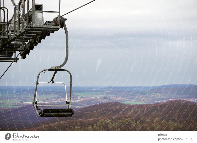 Chairlift with empty 2-seater chair and view of snow-free hill country chair lift Chair lift Cable car Snow free winter sports area Circulating cable car