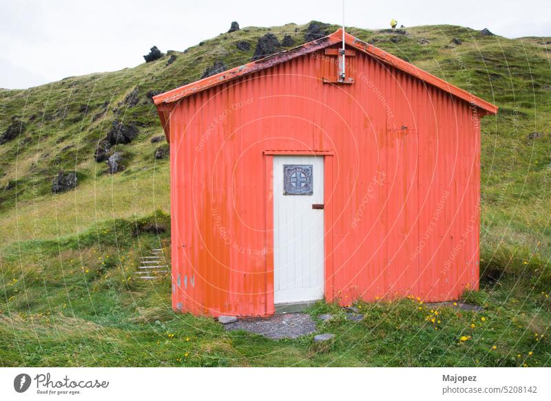 Wooden hut in orange color and white door. Iceland colorful background summer countryside tourism retro exterior wood outdoor rural rustic red house building