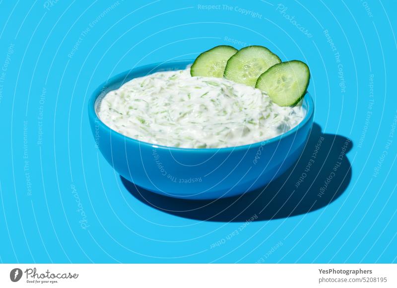 Tzatziki sauce bowl isolated on a blue colored background above appetizer breakfast bright cacik close-up copy space cream cucumber cuisine cut out dairy