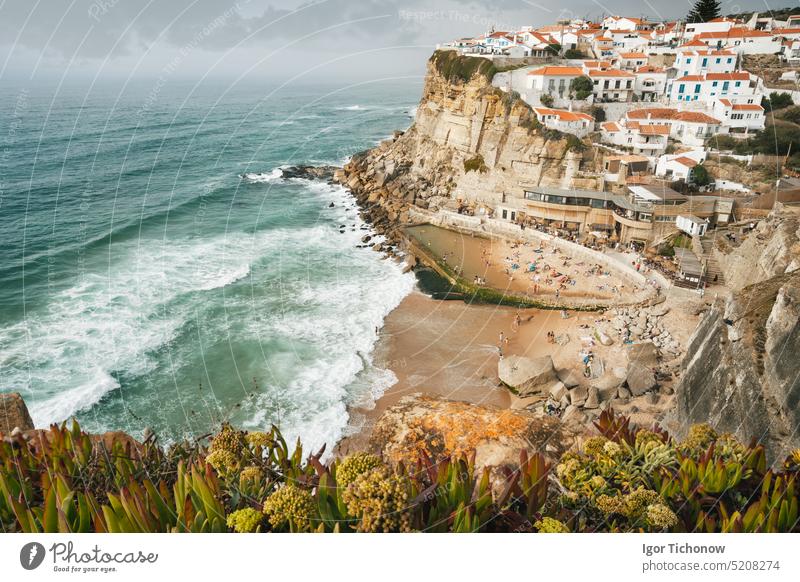 Portugal cute town Azenhas do Mar. Atlantic ocean waves rolling to small beach. White chalk houses build on a cliff edge. Sintra Landmark, Europe travel