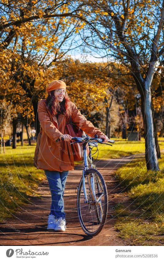 Girl with bicycle at the park leisure healthy outdoor lifestyle bike autumn beret branches brown casual coat colors dry leaves foliage girl glasses happy jeans