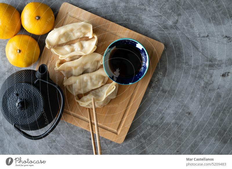 Asian food. Dim sum with soy sauce on bamboo board decorated with oranges and teapot. Copy space. dim sum top view copy space stone background chopstick china