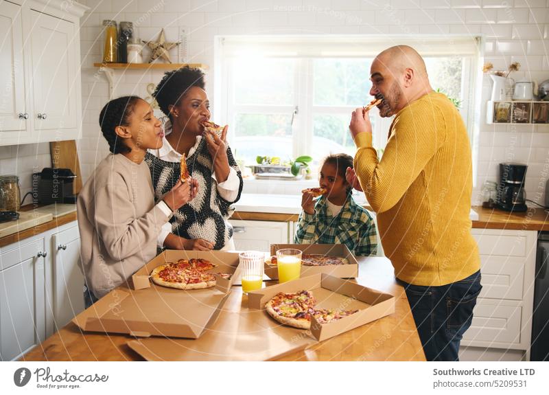 Family eating takeaway pizza at home and laughing family dinner takeout enjoyment multiracial boy down syndrome man woman bite slice meal food anticipation