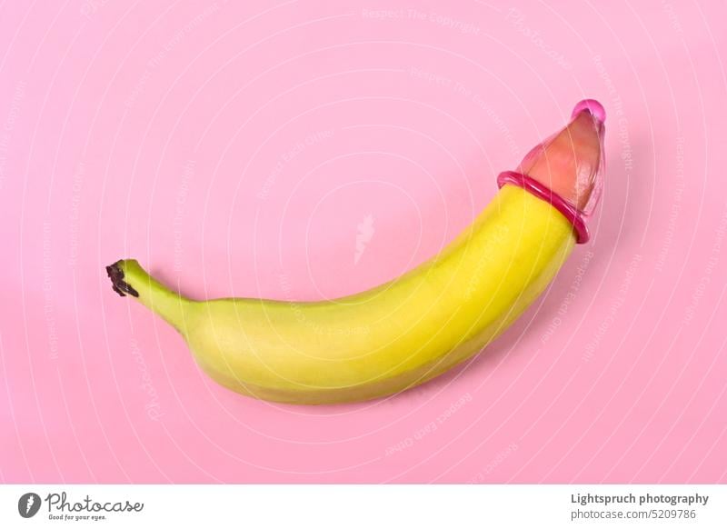 Condom on banana with pink background. Concept of sexual protection. condom symbol sex education sexual issues aids contraceptive erection sex and reproduction