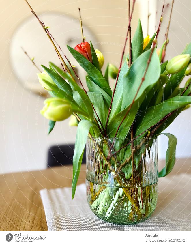 Glass vase with tulips on dining table glass vase Vase Bouquet flowers Spring Easter Living room Dining room Table decoration Interior shot blurriness Green Red