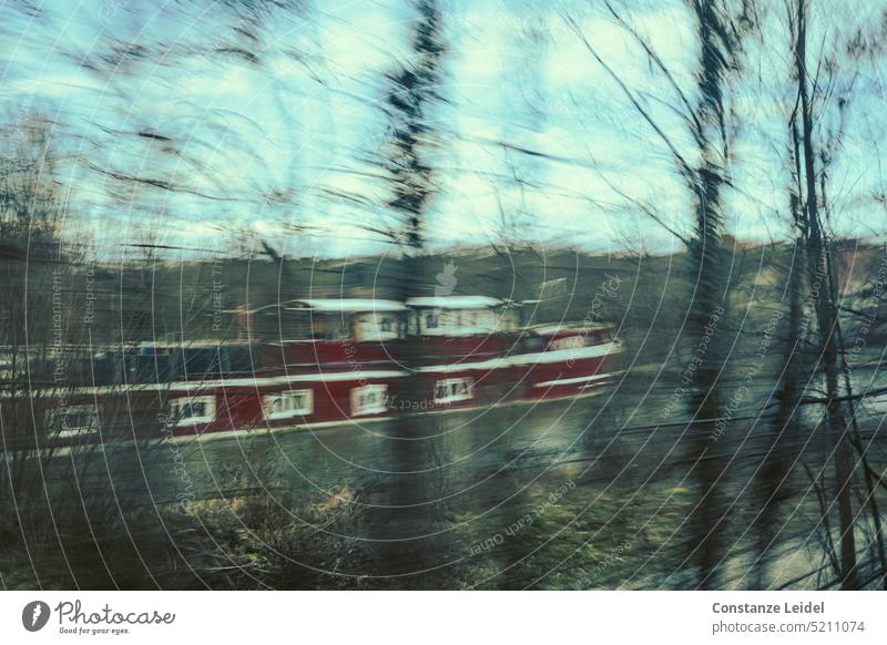 Dark red canal boat behind trees in ICM technique Canal boat ship Old dark red Window moor Channel ICM technology hazy motion blur abstract photography blurred