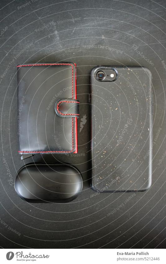 Smartphone, headphones and minimalist wallet in black against black background, contents of a man's bag, Lifestlye flatlay in black and red brown gifts Black