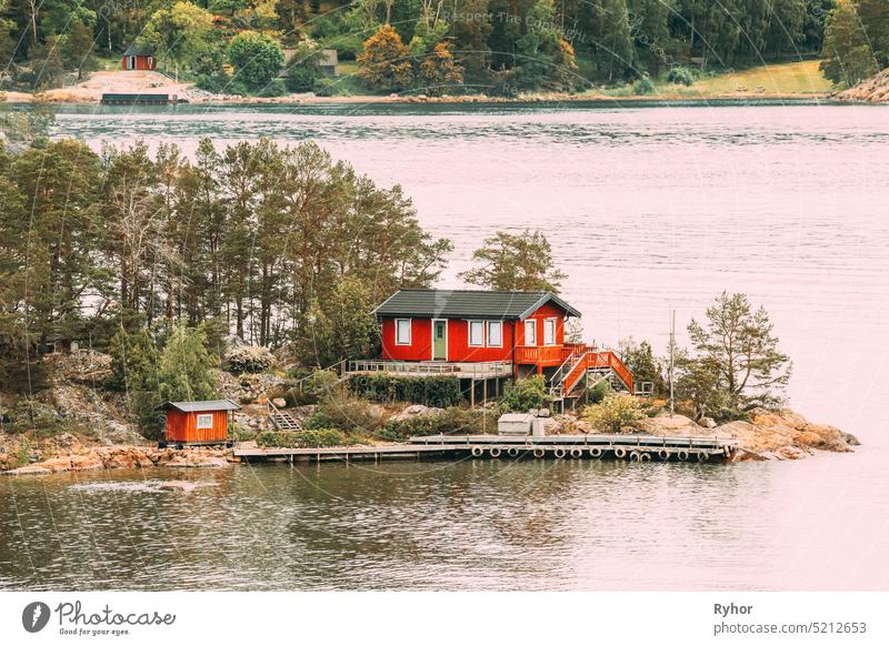 Sweden. Many Beautiful Red Swedish Wooden Log Cabin House On Rocky Island Coast In Summer. Lake Or River Landscape sweden house huts hygge travel nature
