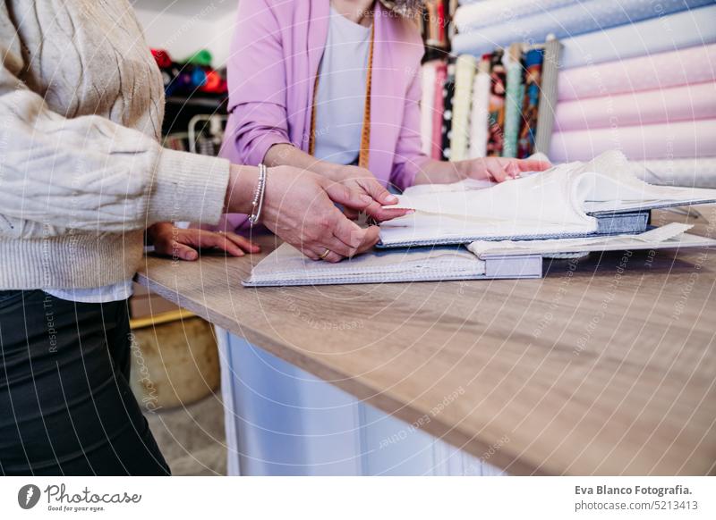 senior woman working in atelier shop with customer showing and sample fabrics. Small business small business ironing job entrepreneur crafts denim profession