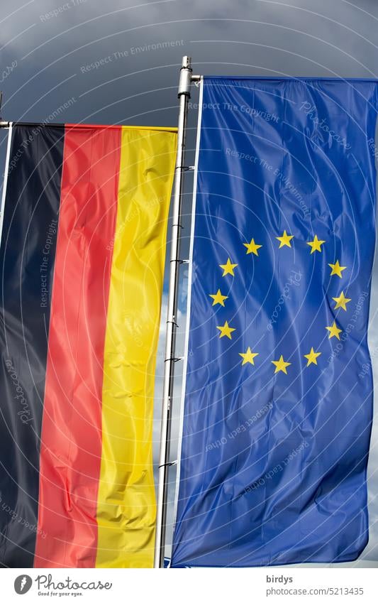 Federal flag and EU flag side by side in front of storm clouds federal flag Europe European Union European flag German flag Politics and state Storm clouds Wind