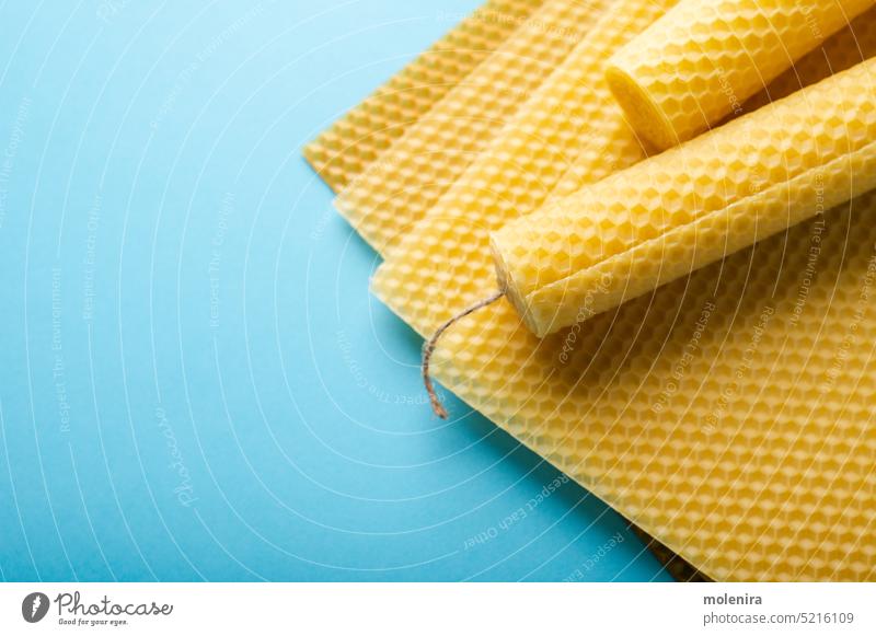 Beeswax honeycomb sheets and candles beeswax material close up cell yellow beehive texture surface pattern organic diy handmade handicraft blue