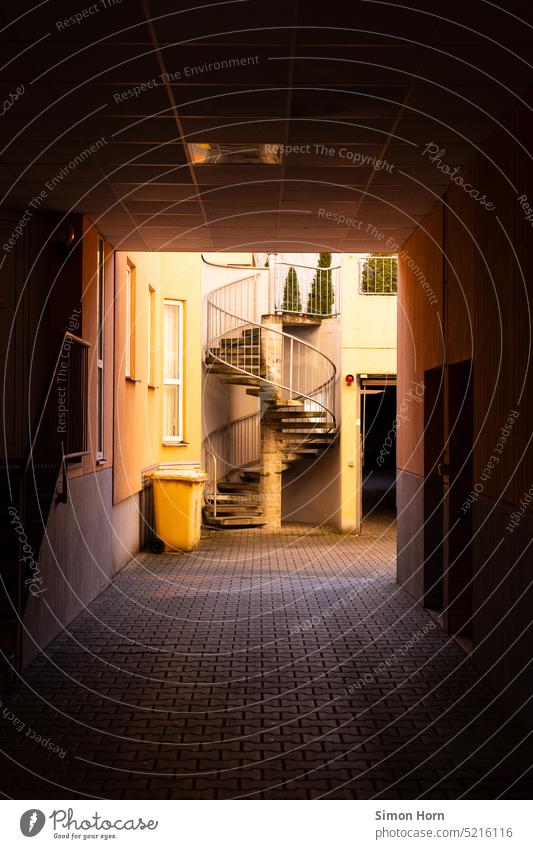 Spiral staircase in backyard Well of light Winding staircase Backyard Stairs rubbish bin upstairs Shaft of light rear building Upward Perspective Yellow