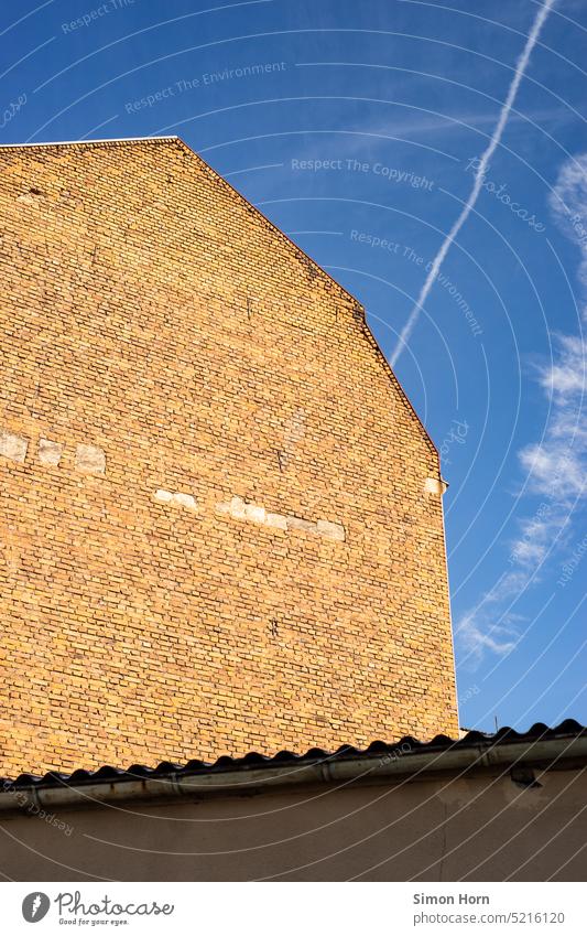 Brick facade against blue sky Sky Vapor trail Facade Wall (building) windowless Manmade structures impressive clinker facade Factory Structures and shapes