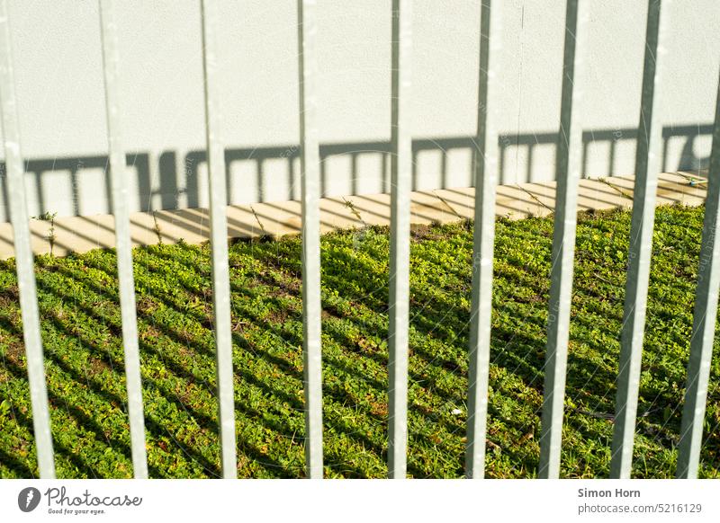 Grille bars cast their shadow on grassy area lattice bars Fence lattice structure Shadow Lawn Barrier cordon Safety nature conservation Structures and shapes
