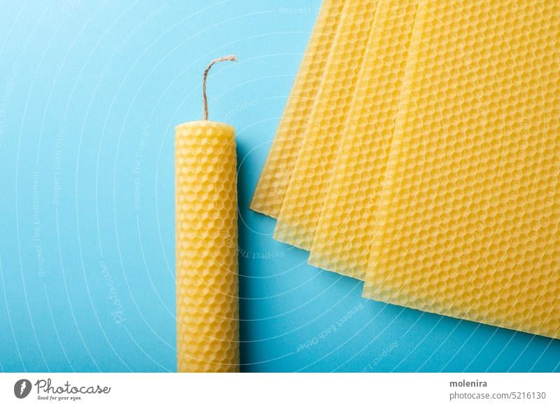 Beeswax honeycomb sheets and candles beeswax material close up cell yellow beehive texture surface pattern organic diy handmade handicraft blue