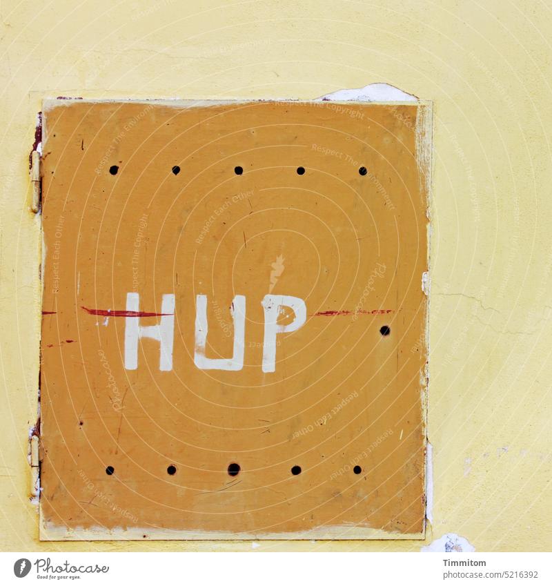 HUP - there's something behind it! Wall (building) Opening Flap Hinge holes Old Lettering Letters (alphabet) Colour question of meaning Mysterious White Yellow