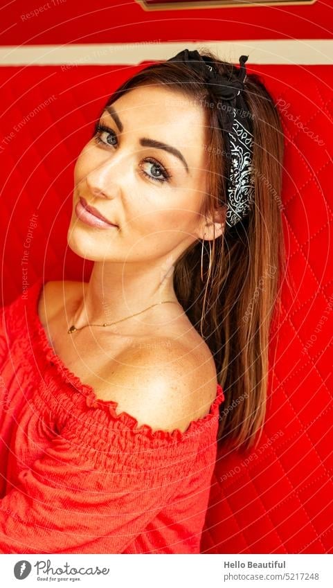 Woman sitting in a red dress in a restaurant brown hair blue eyes Jewellery Model Hairband Red Red couch make-up Shoulder strapless strapless dress Summer