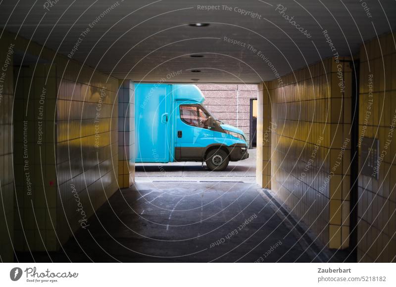 Tiled passageway in gloomy yellow, view of light blue truck, symbolic of delivery traffic and logistics Passage tiles Looking lorry Truck parcels packages Mail
