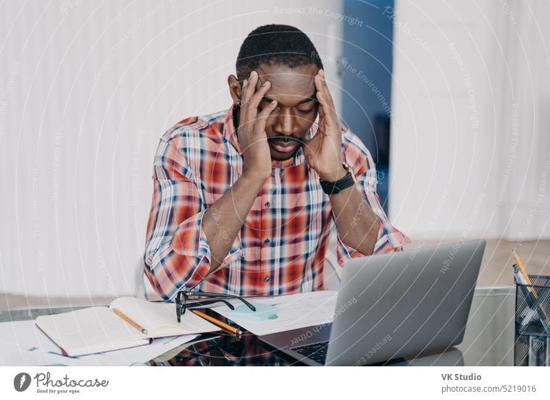 Upset african american male employee blames himself for mistake in work at laptop. Stress, burnout stress tired brainstorm headache job dismissal depression