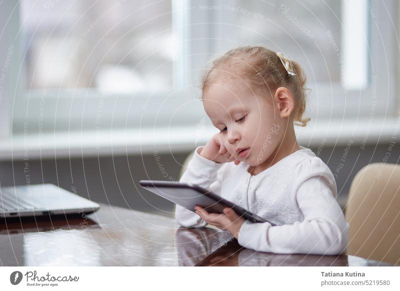 Child with a tablet at the table. Copy space child technology kid digital internet education cute childhood device little home cheerful indoors boy screen art