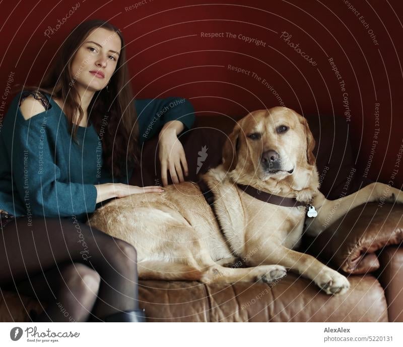 Portrait of young beautiful brunette woman in front of red wall on couch with blonde Labrador - Mo, the best dog in the world Wall (building) Red Sweater